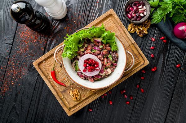 Lobio salad with pomegranate seeds, onion rings, and walnuts on a plate