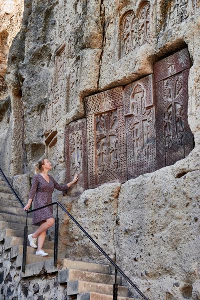 Tourist at Geghard Monastery in Armenia Admiring Stone Khachkars
