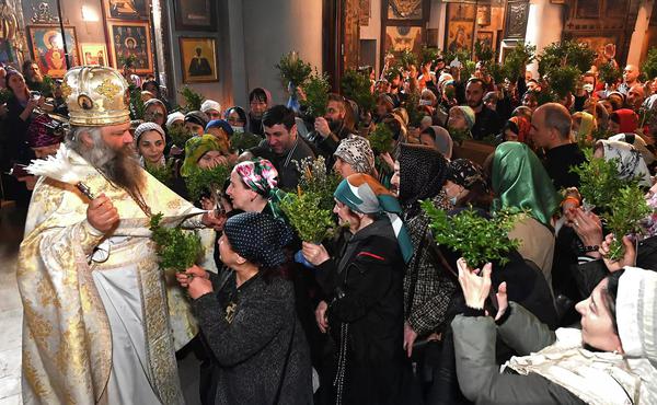 Orthodox priest blessing worshippers holding greenery during an Easter service in Georgia