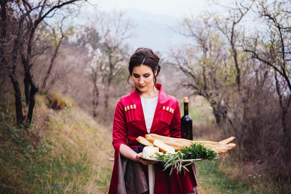 Georgian Girl Wearing Traditional Dress Holding aTtray Full of Traditional Food