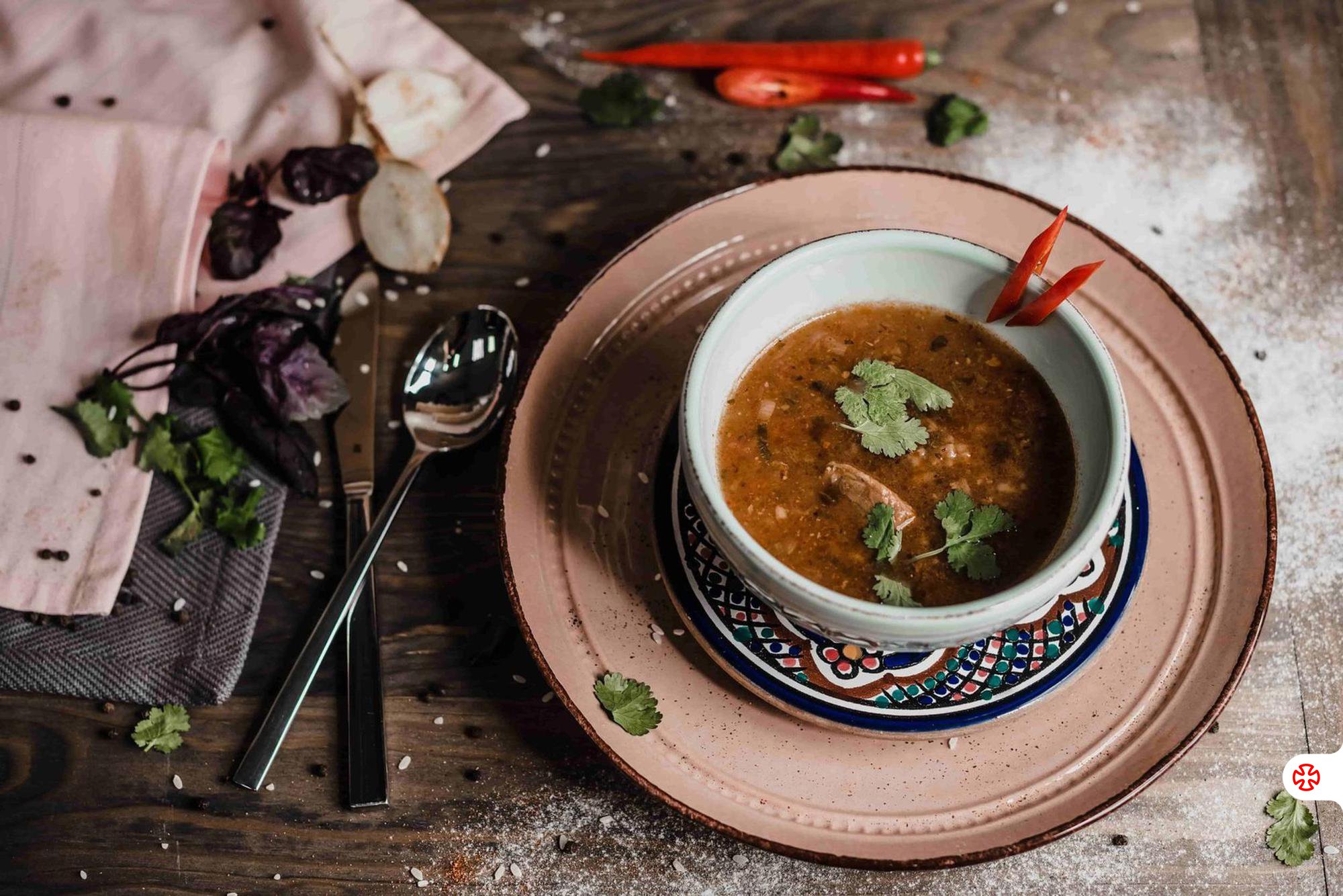 Georgian Kharcho soup in a decorated bowl, topped with cilantro and chili