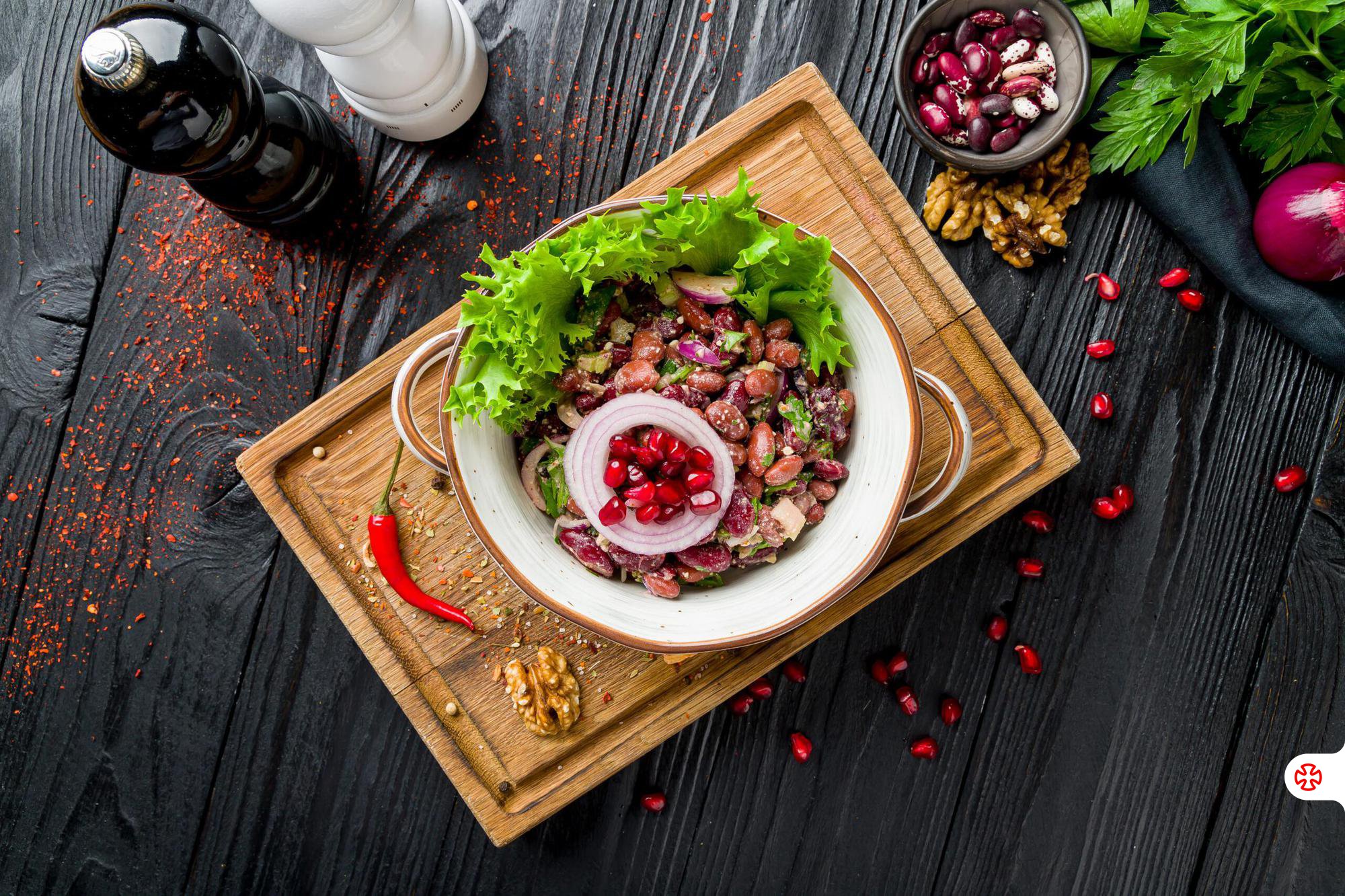 Lobio salad with pomegranate seeds, onion rings, and walnuts on a plate
