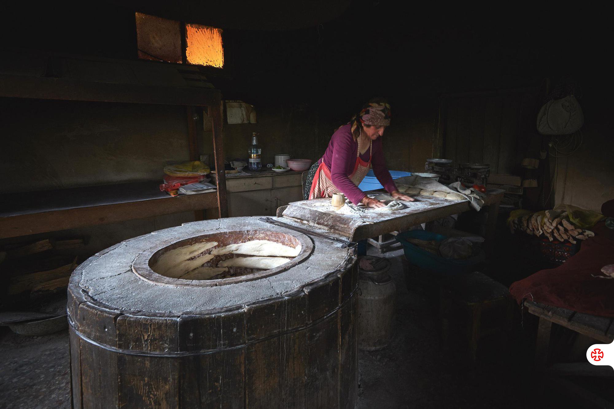 Georgian woman makes traditional bread in old round tandoor oven in Kakheti rural village